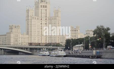Une des sept Sœurs, magnifique gratte-ciel dans le style stalinien, rivière de Moscou et bateaux touristiques. Action. Concept d'architecture, remblai de ville Banque D'Images