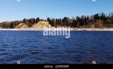 Paysage avec une rivière. Attache. Une rivière gelée au printemps avec une vue sur laquelle vous pouvez voir des forêts et de l'herbe gelées et un ciel lumineux le matin. Banque D'Images