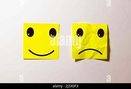 deux notes collées sur le tableau de liège de message avec smiley et triste dessin animé visage expression dans le bonheur contre la dépression et le sourire contre l'adversité concept Banque D'Images