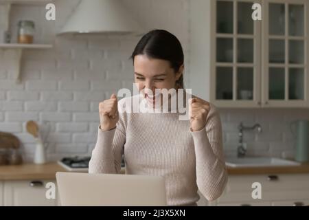 Joyeuse fille excitée regardant l'affichage avec le gagnant oui mains Banque D'Images