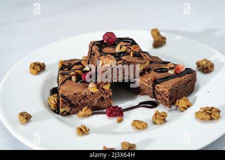 Carrés de brownie au chocolat avec morceaux de noix, fils de chocolat et granola. Concept d'alimentation naturelle et saine. Vue en hauteur. Banque D'Images