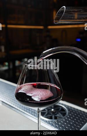 L'homme sommelier verse le vin rouge dans un décanteur pour l'aération du goût et de l'arôme Banque D'Images