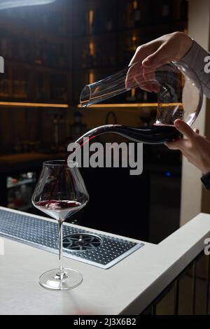 L'homme sommelier verse le vin rouge dans un décanteur pour l'aération du goût et de l'arôme Banque D'Images