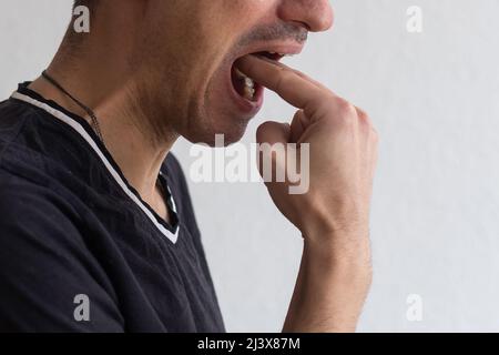 homme dégoûté avec le doigt dans la bouche déplaisé prêt à jeter isolé sur fond de mur gris. Langage corporel émotionnel humain. Banque D'Images