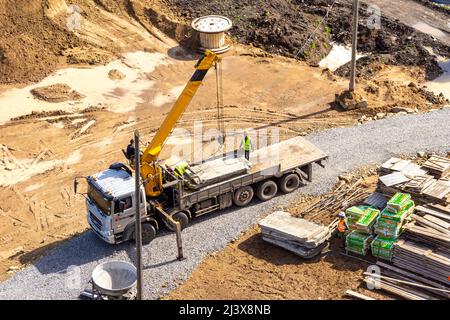 Kemerovo, Russie - 24 juin 2021. Un camion surdimensionné doté d'une plate-forme de chargement étendue et d'une grue pour le chargement et le déchargement de marchandises se trouve sur un c Banque D'Images