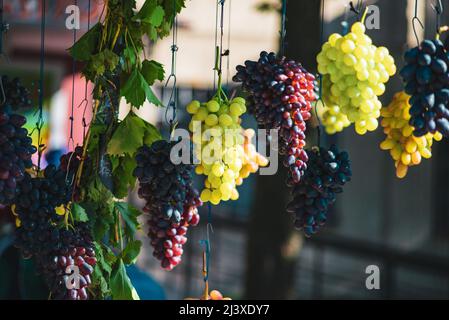 Des grappes de raisins de différentes variétés sont suspendues dans la rue. Banque D'Images