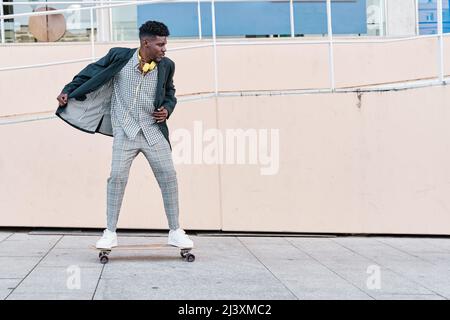 jeune homme d'affaires à bord d'un skateboard en costume Banque D'Images