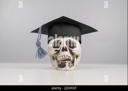 Crâne en plastique avec bonnet et lunettes universitaires. Banque D'Images