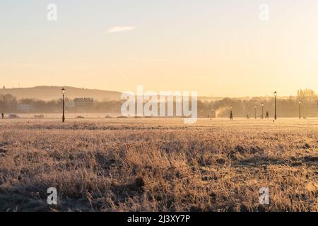 Une vue sur Blackheath Common en hiver pendant un coucher de soleil chaud. On peut voir les gens profiter de leur matinée. Banque D'Images