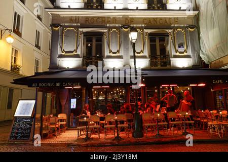 Les gens assis dans un café traditionnel français au rocher de Cancale sur la rue Montorgueil rue à la nuit des pluies, Paris, France. Banque D'Images