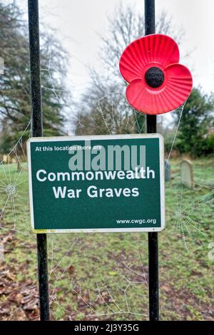 Warminster, Wiltshire, Royaume-Uni - janvier 18 2022 : un panneau Commonwealth War graves et un coquelicot rouge en plastique souvenir sur une porte de chantier naval à l'église St Johns Banque D'Images