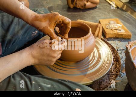 poterie, atelier, concept d'art céramique - gros plan sur les mains masculines sculptez un nouvel ustensile avec des outils et de l'eau, les doigts de l'homme travaillent avec la roue de potier et ra Banque D'Images