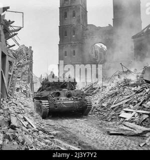 L’armée britannique en Europe du Nord-Ouest 1944-45 Un char Cromwell de 15th/19th King’s Royal Hussars, 11th Armoured Division, avec infanterie à bord, avance dans les décombres d’Uedem, Allemagne, 28 février 1945. Banque D'Images