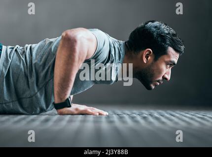 Mise au point avant. Coupe courte d'un jeune athlète masculin en train de faire des push-up sur fond gris. Banque D'Images