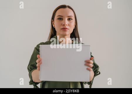 Sérieuse belle jeune femme tenant un tableau vide avec espace de copie pour le texte dans les mains comme maquette pour le design. Banque D'Images