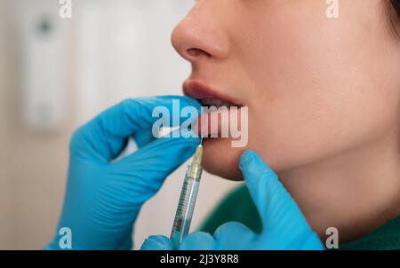 La jeune femme reçoit un mastic hyaluronique ou une injection cosmétique de botox dans les lèvres, gros plan. Soin du visage rajeunissant. Banque D'Images