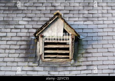 Un ancien évent d'air avec des lattes en bois dans un état de réparation sur un toit en tuiles givrées Banque D'Images