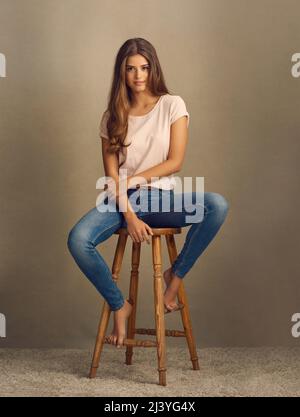 savez-vous à quel point vous êtes parfait ? Photo studio d'une belle jeune femme assise sur un tabouret sur un fond plat. Banque D'Images