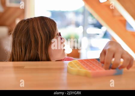 Une fille joue avec un jouet sensoriel antistress coloré pousser le pop Banque D'Images