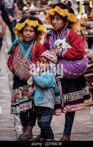 Enfants quechua, deux filles et un garçon vêtus de vêtements traditionnels au marché du dimanche de Pisac, Pérou Vallée sacrée Banque D'Images