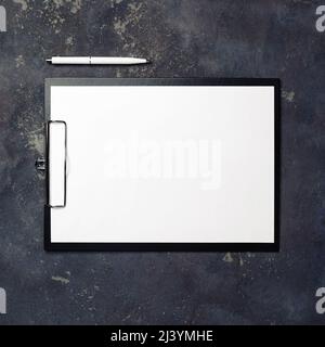 Presse-papiers avec papier vierge et stylo sur fond en béton. Vue de dessus. Banque D'Images