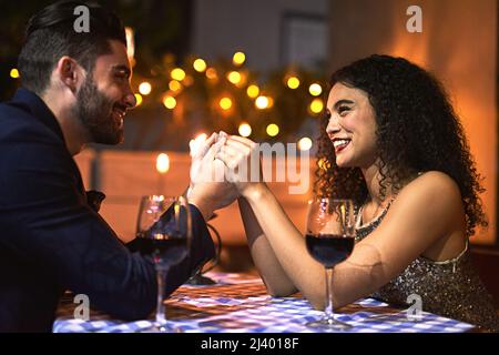 Nous resterons ensemble pour toujours. Photo d'un jeune couple gai tenant les mains tout en regardant dans les yeux les uns les autres au-dessus d'une bougie allumée dîner date à Banque D'Images