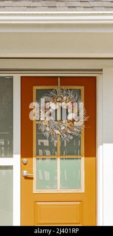 Porte avant avec couronne, vue avant d'une maison accueillante. Porte d'entrée d'une maison luxueuse. Personne, mise au point sélective, photo de rue Banque D'Images