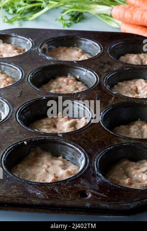 Moule à muffins au four foncé rempli de pâte à muffins aux gâteaux de carottes. Banque D'Images