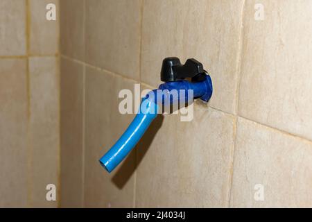 Le robinet d'eau bleu en plastique se trouve dans la salle de bains Banque D'Images