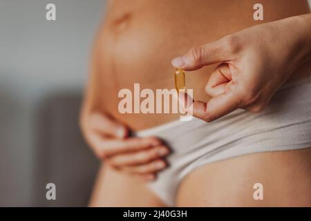 Suppléments prénatals pendant la grossesse. Femme enceinte qui mange de la vitamine oméga 3 d'huile de morue au premier trimestre pour le développement du cerveau Banque D'Images