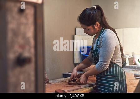 Fabrication avec précision et soin. Photo d'une artiste en céramique travaillant sur sa poterie dans un atelier. Banque D'Images