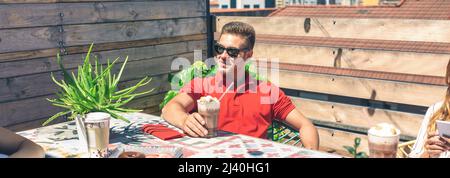 Homme prenant un verre sur une terrasse Banque D'Images