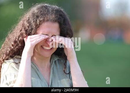 Femme stressée se grattant les yeux qui démangent à pied dans un parc Banque D'Images