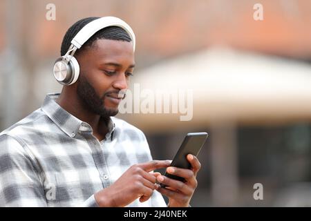 Homme à la peau noire portant des écouteurs écoutant de la musique dans la rue Banque D'Images