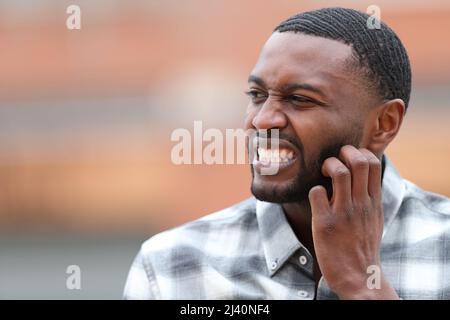 Homme avec la peau noire rayant la barbe itchy dans la rue Banque D'Images