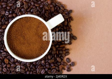 Grains de café fraîchement torréfiés sur fond de couleur et café moulu dans une tasse sur le dessus. Arrière-plan et texture disponibles Banque D'Images