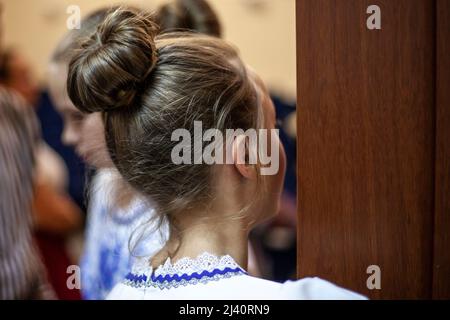 Coiffage de cheveux attachés dans un petit pain. La fille regarde par la porte. Un adolescent avec une coupe de cheveux classique. Vue arrière de la tête humaine. Banque D'Images