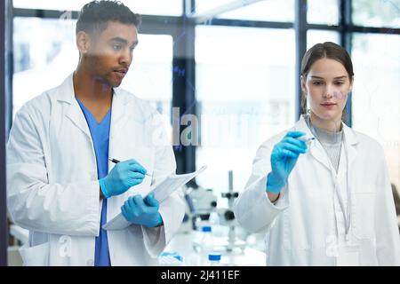 Faire le calcul pour prouver leur théorie. Photo de deux scientifiques qui ont résolu des équations sur un écran en verre dans un laboratoire. Banque D'Images