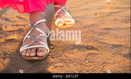 Les pieds des femmes sur une promenade dans le désert donnant une sensation de détente pendant que le soleil se couche. Banque D'Images