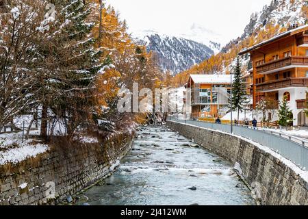 Zermatt, Suisse - 11 novembre 2019 : paysage urbain de rivière à fleurs plates, à côté d'une rue piétonne et de vieux résidents avec fond de m enneigé Banque D'Images