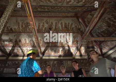 Les touristes prêtent attention aux vieilles peintures de style kamasan sur les plafonds du pavillon Kertha Gosa, une ancienne salle de réunion où les dirigeants traditionnels ont discuté des questions de justice, situé dans la région du complexe du palais de Klungkung aboli Semarapura, Klungkung, Bali, Indonésie. Banque D'Images