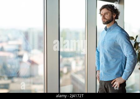 Portrait d'un homme d'affaires confiant regardant à travers la fenêtre Banque D'Images