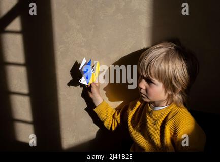 Ombres sur le mur d'une colombe en papier de la paix et d'un garçon triste. Les Ukrainiens demandent la paix, le jeu de l'ombre et de la lumière, le portrait dramatique. Les gens le sont Banque D'Images