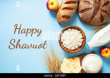 Joyeux concept de vacances juif Shavuot. Produits laitiers, wheats, fromage cottage dans un bol, fromage, pain, pommes, bouteille de lait sur fond bleu Banque D'Images