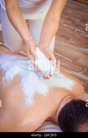 Une femme guérisseur exécute un rituel avec du sel, verse du sel sur le dos d'un homme couché. Détente. Banque D'Images