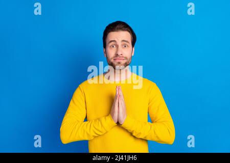 Portrait d'attrayant inquiet brunet gars demandant cadeau de faveur présent isolé sur fond bleu clair de couleur Banque D'Images