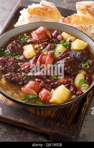 La recette traditionnelle de Sopa da Pedra combine des haricots rouges, des pommes de terre, de la viande séchée et des saucisses dans l'assiette sur la table. Verticale Banque D'Images