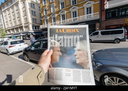 Paris, France - 11 avril : un homme regig en centre-ville le journal français la Croix Emmanuel Macron, Marine le Pen un jour après le premier tour de l'élection présidentielle française du 10 2022 avril - le titre de la confrontation Banque D'Images