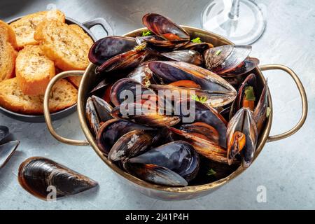 Moules cuites dans une poêle de cuivre, cuisine belge ou française dans un restaurant, avec pain grillé Banque D'Images