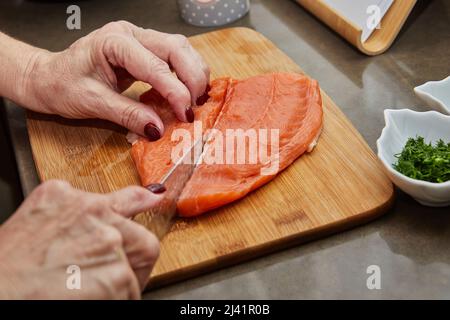 Le chef coupe du saumon avec un couteau pour préparer la recette Banque D'Images